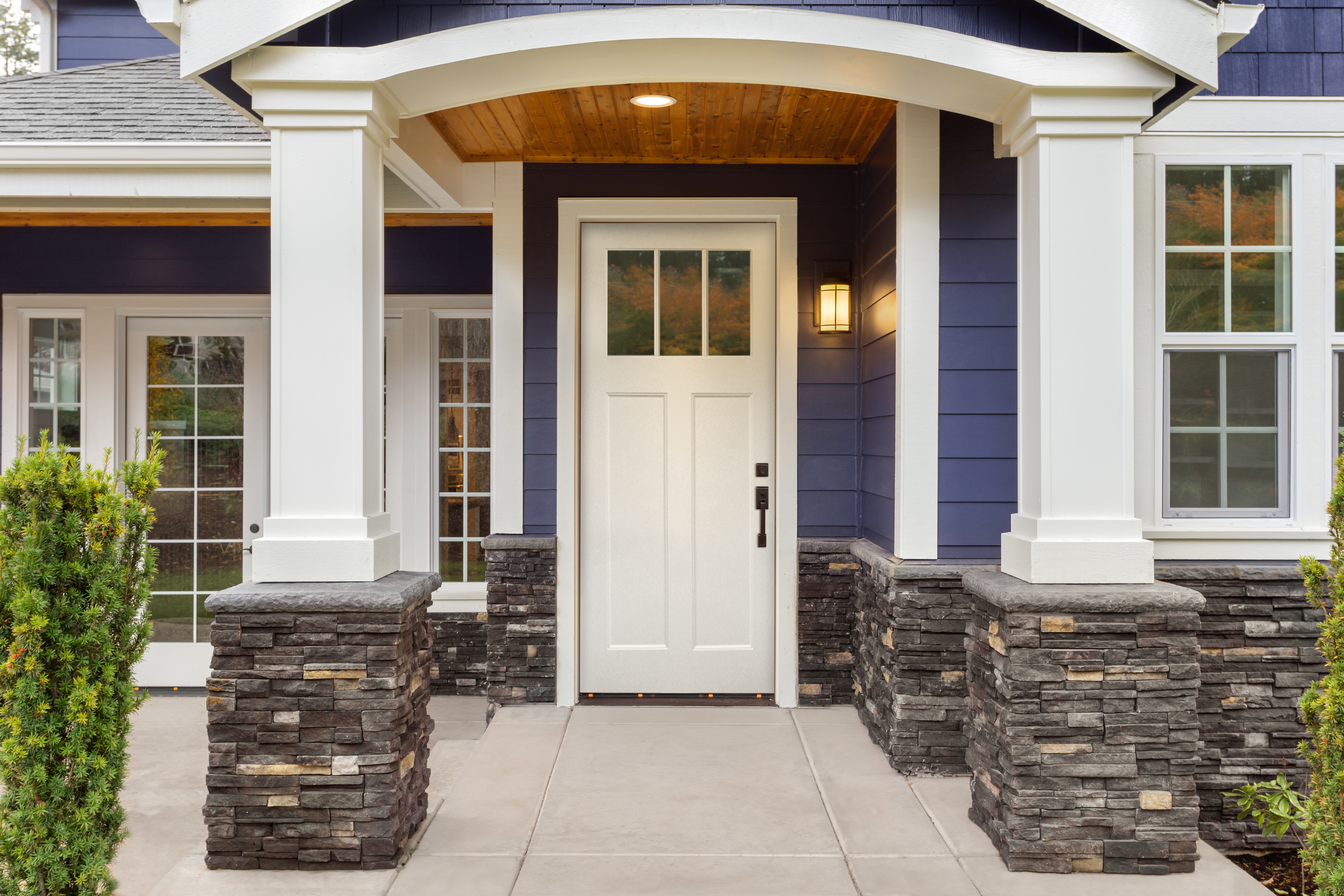 Close-up of white and blue home with a craftsman style entry door.