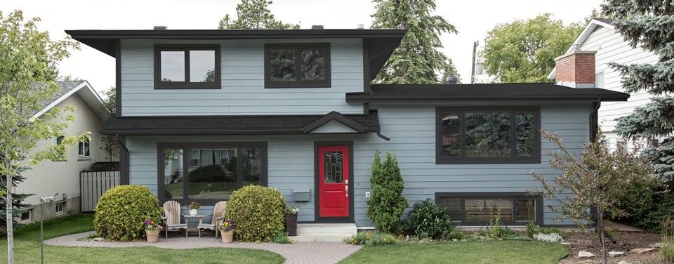 Two storey home with grey siding. The home features dark grey framed uPVC windows and a bright red single entry door.